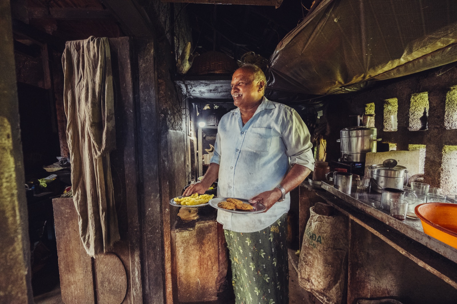 Mohanan at his vintage village tea house with plates of fritters