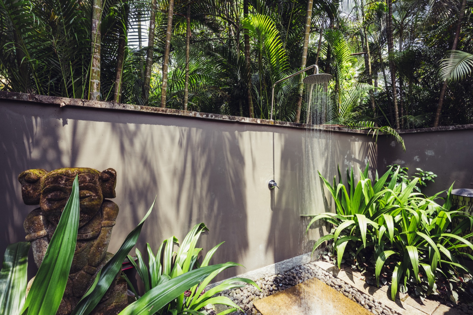 A garden shower watched over by a carved stone face